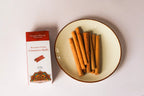 Ceylon Cinnamon sticks on a plate with a box labeled 'Cinnamon Heritage' on a white background