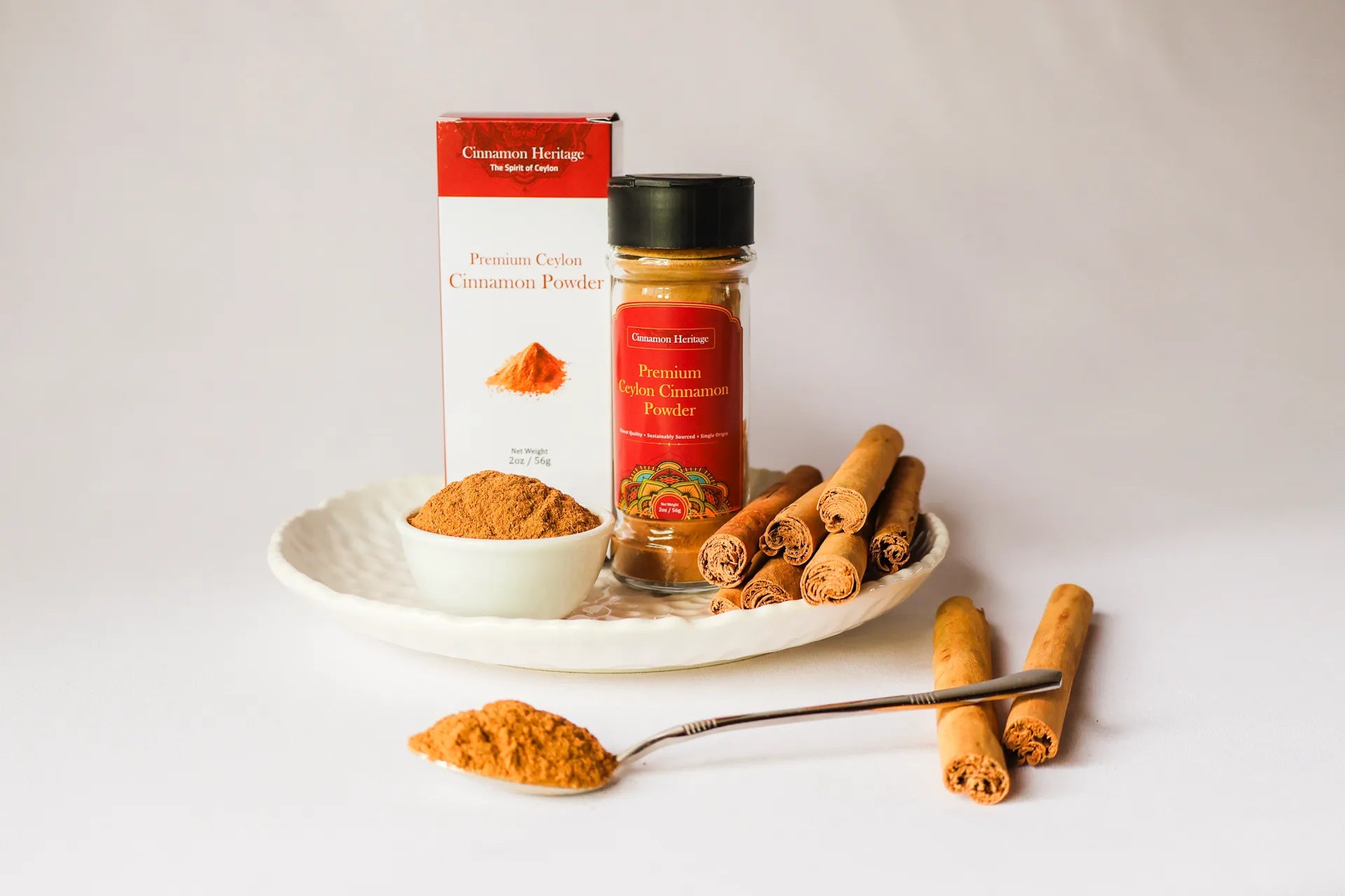 Buy Ceylon Cinnamon powder packaging, jar, and cinnamon sticks on a white plate with a white background